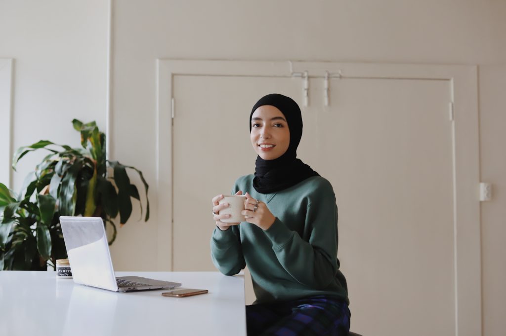 A woman in a hijab uses a laptop while raising funds for a nonprofit organization. 