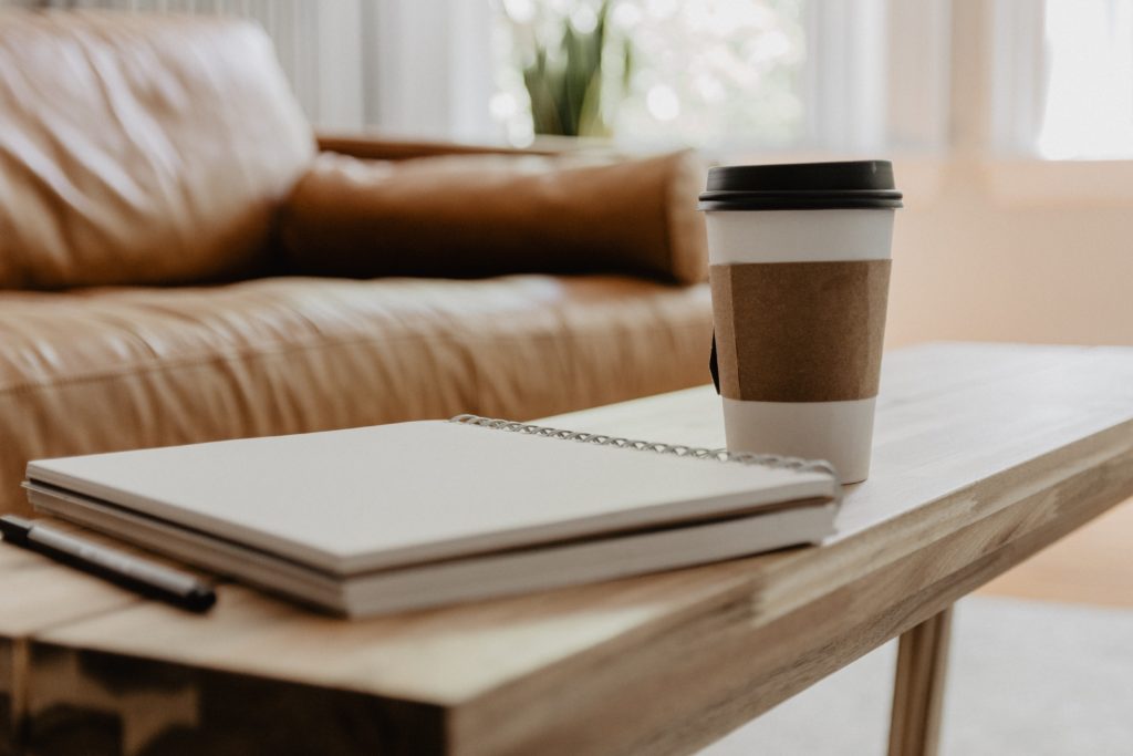  A coffee cup and a notebook sit on a coffee table, as user plans out Facebook ads for nonprofits.